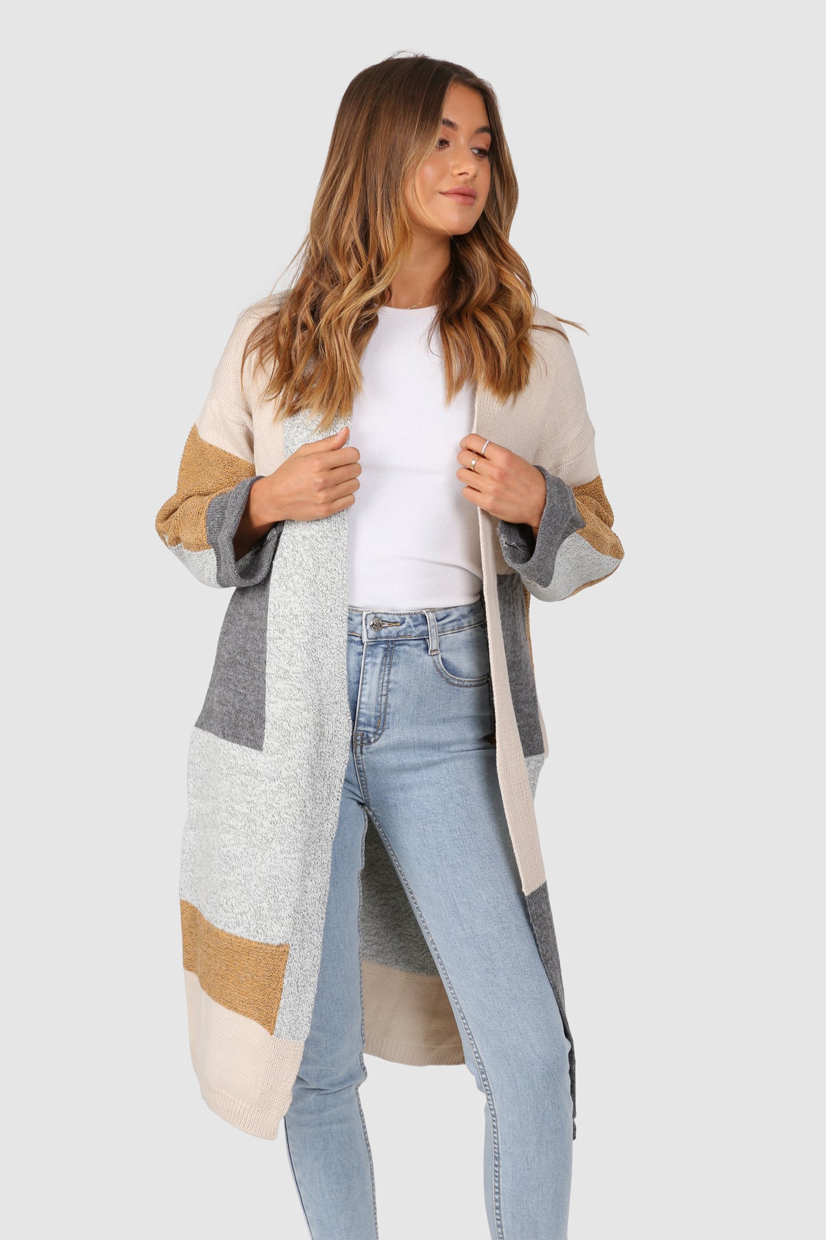 Bailage Caucasian female wearing Oversized Open Front  Multi-Color  Two Sided Pockets  Mid-Length  Relaxed Fit  Color Blocking Pattern  Ribbed Hemline and Details  Relaxed Fit  Casual Cardigan paired with a scoop neck white tee with high waisted light wash denim jeans and white sneakers