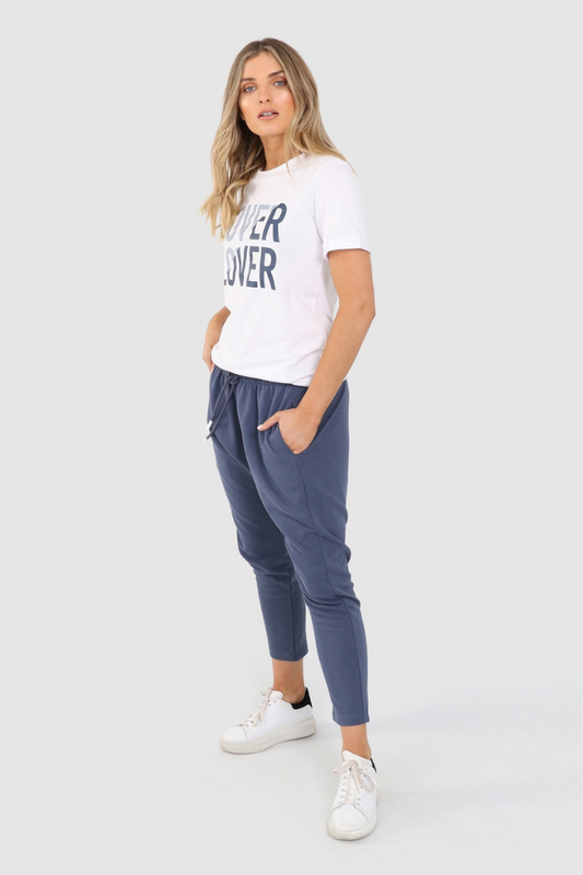 Tall Blonde Caucasian female wearing Adjustable Drawstring  Drop Crotch pants  Long Cotton-Blend Joggers  Two Front Deep Pockets  Casual Loungewear paired with graphic white t-shirt and white sneakers