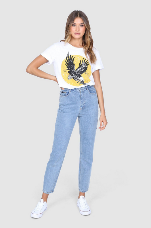 Bailage Haired Caucasian Female wearing aVintage  Casual  Eagle Graphic Tee  Cotton Short Sleeved T-Shirt  Relaxed Fit  Round Neck Top paired with high waisted light washed mom jeans and white converse