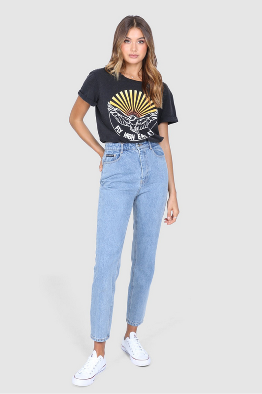 Bailage Curled Haired Caucasian female wearing Vintage  Cotton Casual  Graphic Tee  Short Sleeved T-Shirt  Relaxed Fit  Round Neck  70's vibe paired with high waisted light washed denim jeans and white converse 