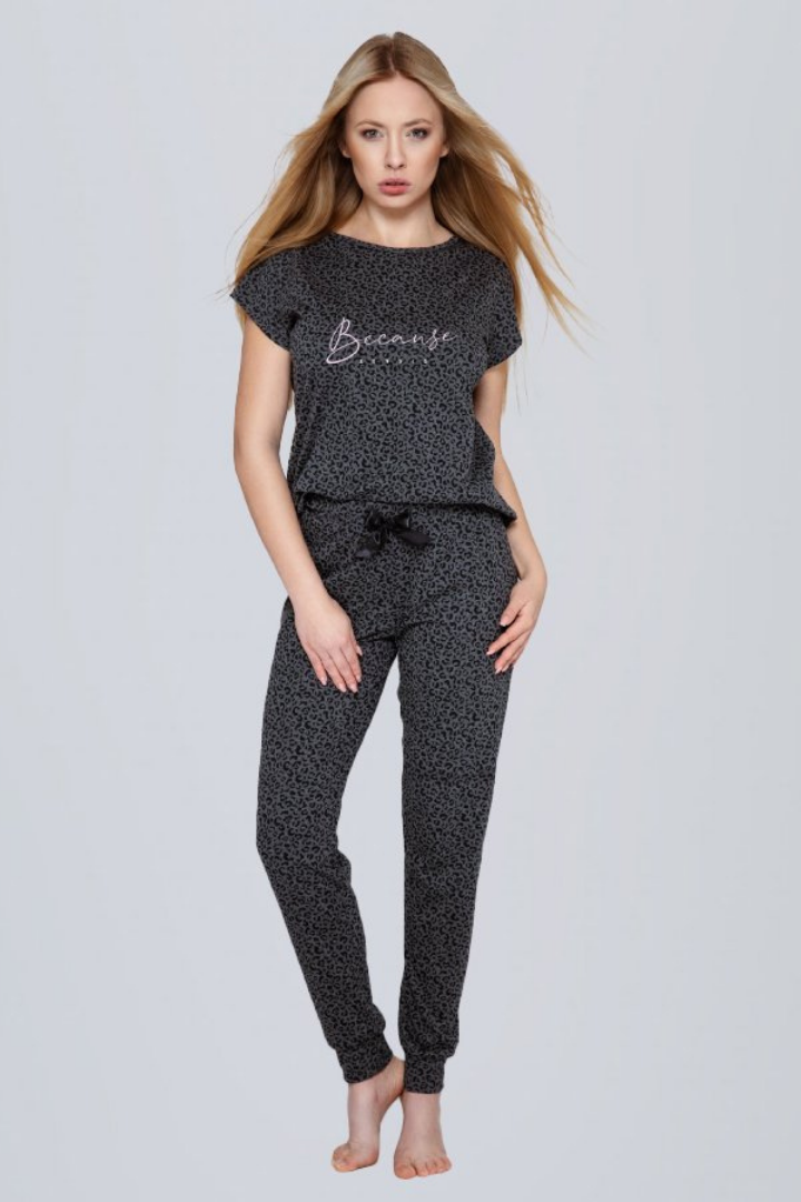 A Tall Blonde Caucasian female wearing a Two piece outfit set Cotton-Blend Short Sleeve Top  Leopard Print Pattern  Soft Casual T-shirt  Long Pant Jogger  Cuff Ankles  Adjustable Satin Bow Tie  Sustainable pyjama set Eco-conscious lounge Wear 