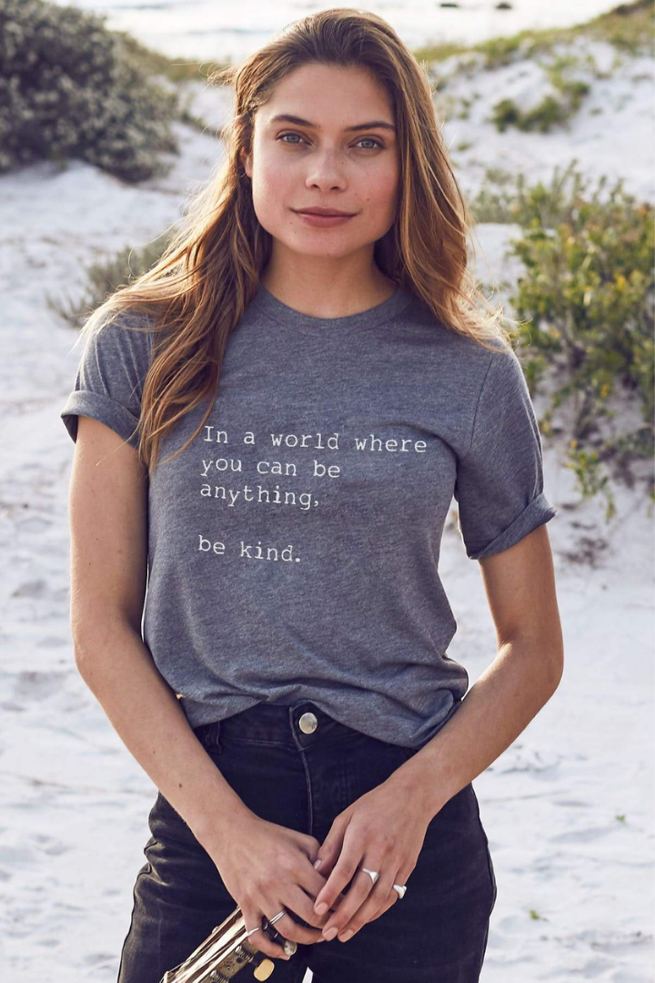 A Brunette with blonde highlights Caucasian female wearing a Casual Basic Quoted Graphic Tee Short Sleeved T-Shirt Relaxed Fit Lightweight Poly-Viscose Blend Soft Round Neck Pullover Top paired with dark denim jeans and 4 sliver rings accessories