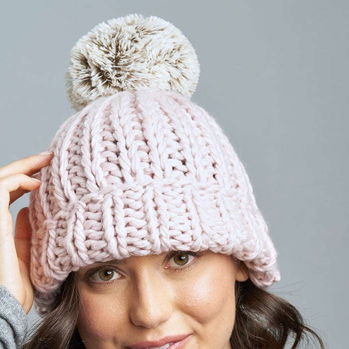 Brunette Caucasian Female wearing Chunky Cable Knit Faux Fur Pom Pom Ribbed Detailed Timeless Winter Accessory Stretchy Toque Easy Slip On Beanie in Blush