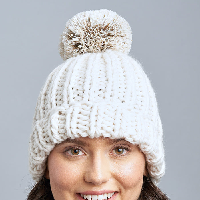 Brunette Caucasian Female wearing Chunky  Cable Knit  Faux Fur Pom Pom  Ribbed Detailed  Timeless Winter Accessory  Stretchy Toque  Easy Slip On Beanie in Ivory