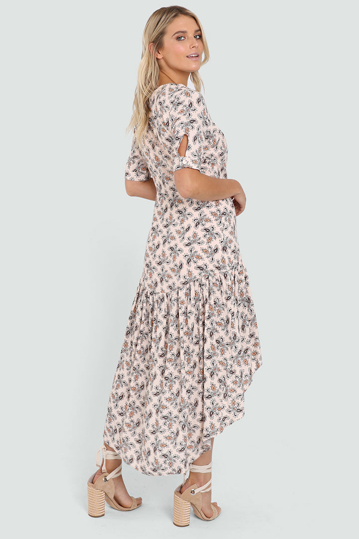 Tall Blonde Caucasian Female wearing a V-Neckline  Ruffled Bottom  Mid-Arm Sleeve  Multi-Colored  Paisley Patterned  Maxi Dress  High Low Spring Dress  Waterfall Bottom Summer Dress Button Details paired with tie up open toe block heels