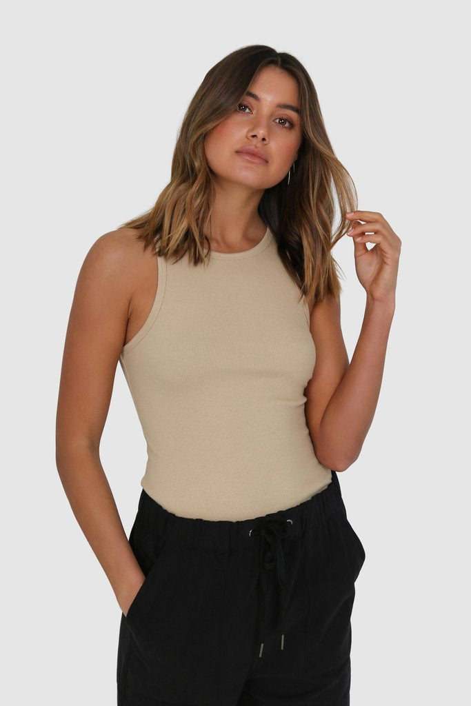 Bailage Short Haired Caucasian Female wearing High NeckLine Sleeveless Basic Ribbed Cotton Bodycon Tank Figure-hugging Casual top paired with long loosely fit elastic joggers with adjustable drawstrings and open toed two strap black sandals